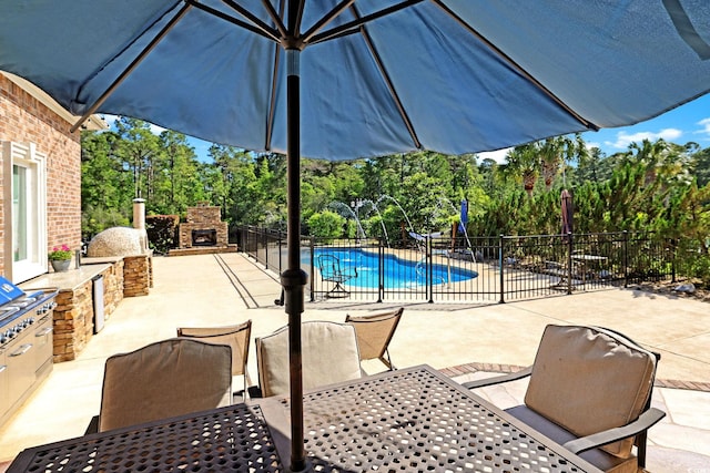 view of patio / terrace with an outdoor stone fireplace, fence, outdoor dining space, and a fenced in pool