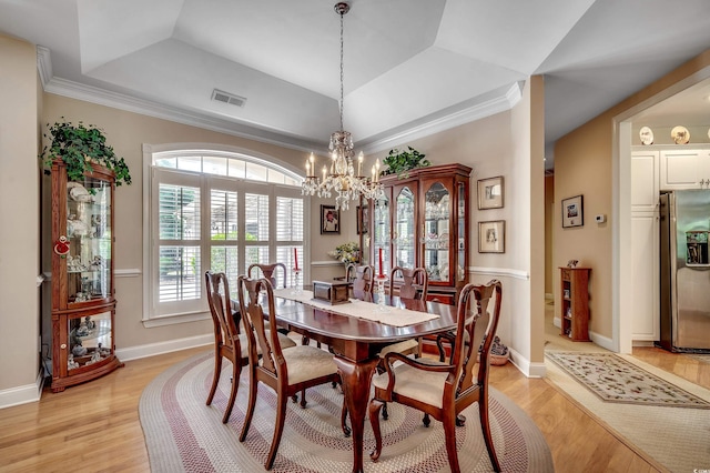 dining area featuring visible vents, ornamental molding, light wood-style floors, baseboards, and a chandelier