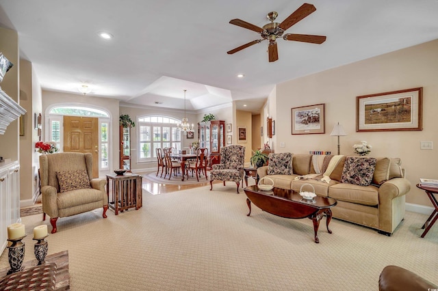 living room featuring baseboards, recessed lighting, a tray ceiling, carpet, and ceiling fan with notable chandelier