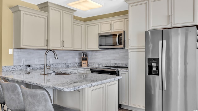 324 S Waccamaw Dr, Garden City Beach, SC 29576 - kitchen featuring a sink, a peninsula, stainless steel appliances, backsplash, and light stone countertops
