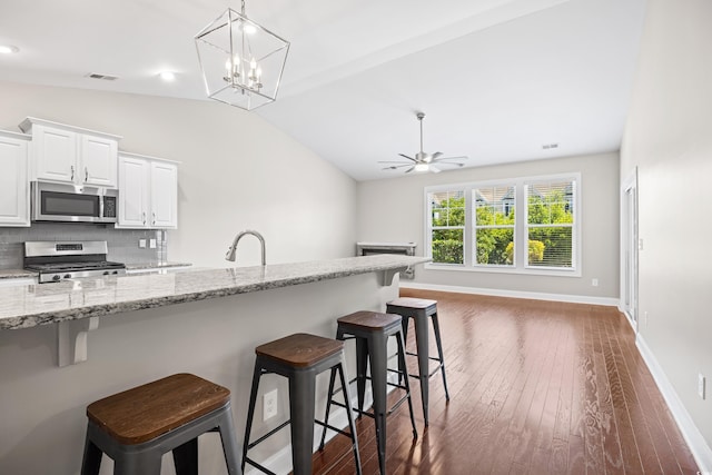 kitchen with visible vents, dark wood-style flooring, lofted ceiling, a breakfast bar area, and appliances with stainless steel finishes