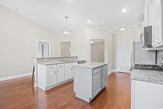 kitchen with a sink, a center island, white cabinets, and stainless steel microwave