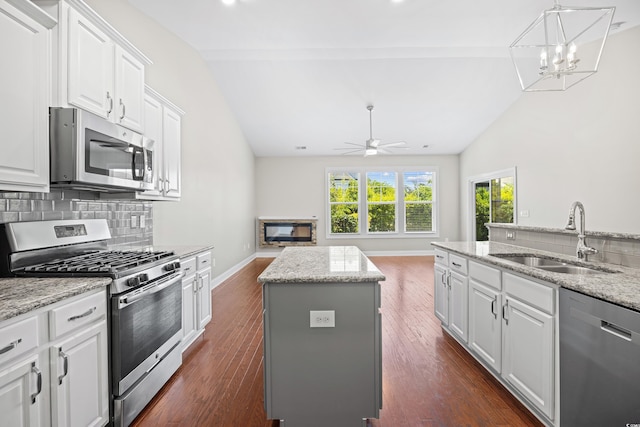kitchen featuring a center island, a sink, appliances with stainless steel finishes, and vaulted ceiling