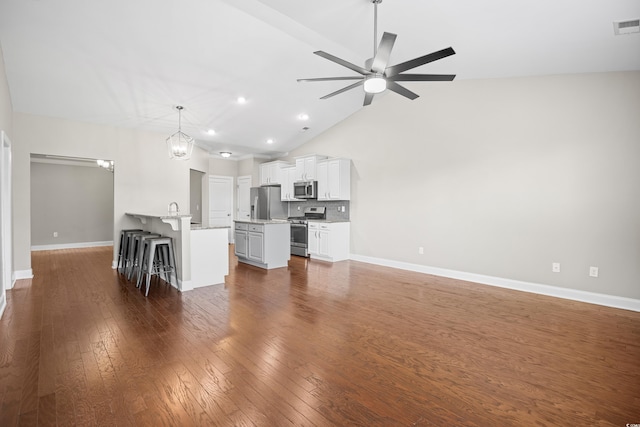 unfurnished living room featuring recessed lighting, dark wood finished floors, ceiling fan with notable chandelier, and baseboards