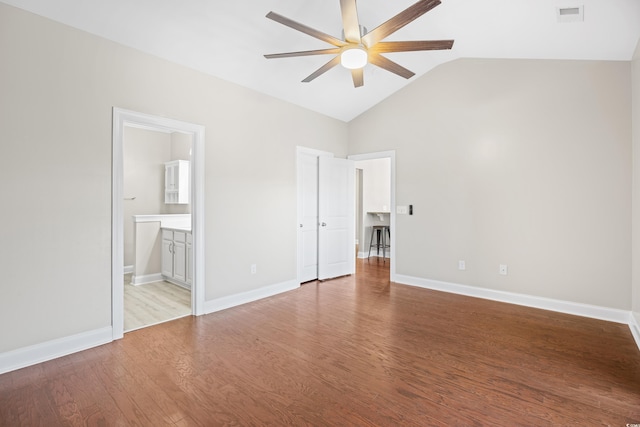 unfurnished bedroom featuring connected bathroom, light wood-style floors, baseboards, lofted ceiling, and visible vents