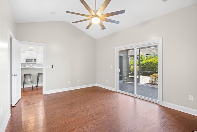 empty room with dark wood-type flooring, baseboards, ceiling fan with notable chandelier, and vaulted ceiling