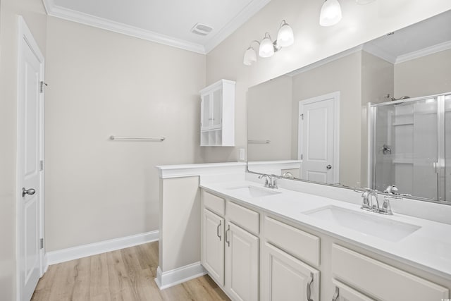 bathroom with a stall shower, ornamental molding, a sink, and wood finished floors