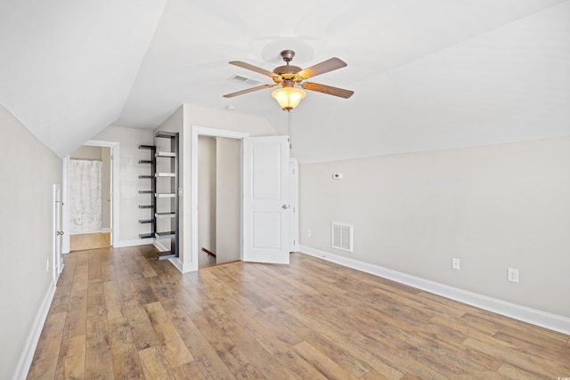 additional living space featuring a ceiling fan, visible vents, hardwood / wood-style flooring, baseboards, and lofted ceiling