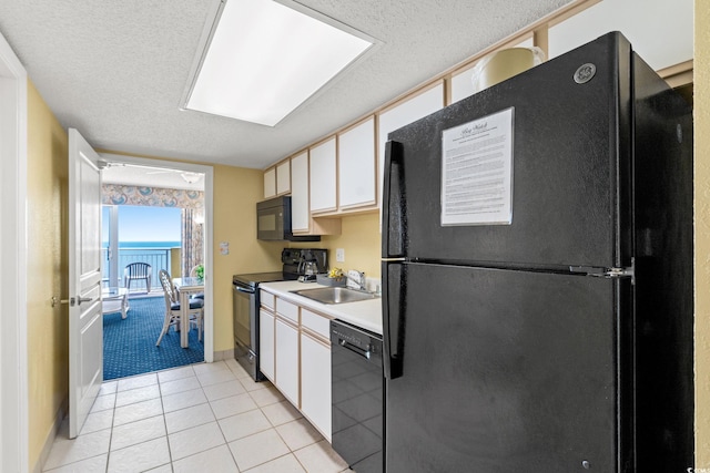 kitchen featuring black appliances, a sink, a textured ceiling, light countertops, and white cabinetry