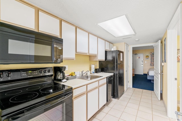 kitchen featuring black appliances, a sink, light countertops, white cabinetry, and light tile patterned flooring