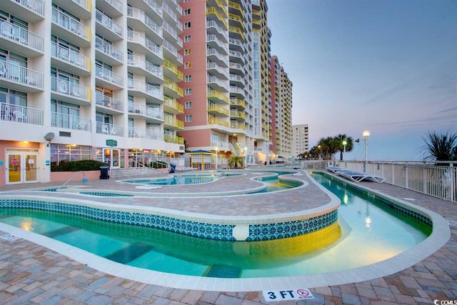 pool at dusk featuring a community pool