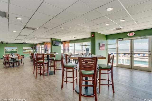 dining space with wood finished floors, recessed lighting, and a paneled ceiling