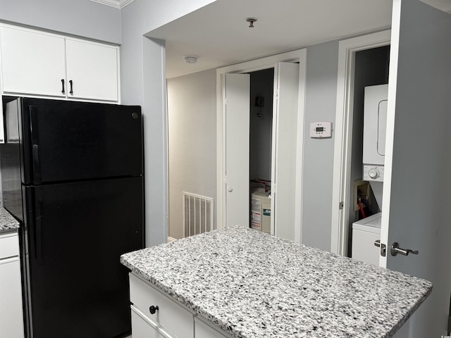 4350 Intercoastal Dr Unit 2302, Little River, SC 29566 - kitchen with freestanding refrigerator, stacked washing machine and dryer, white cabinets, light stone countertops, and a center island