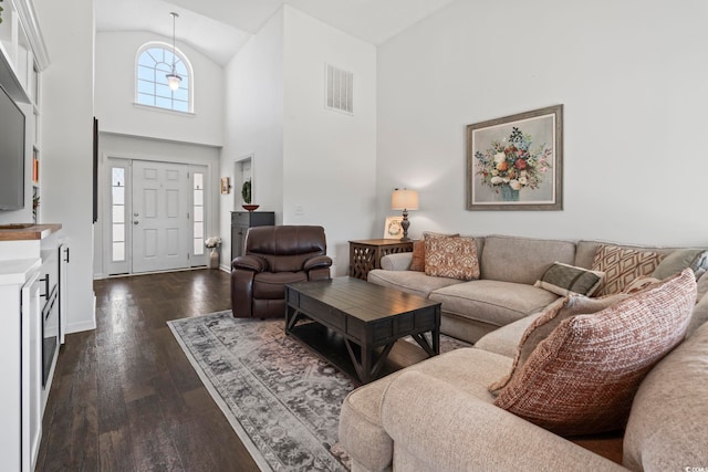 living area with visible vents, dark wood finished floors, baseboards, and high vaulted ceiling
