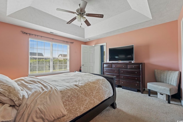 bedroom featuring ceiling fan, carpet, a tray ceiling, and visible vents