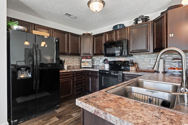 kitchen with dark brown cabinets, a sink, dark wood-type flooring, visible vents, and black appliances