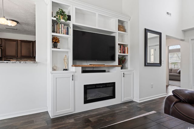 living room featuring a glass covered fireplace, baseboards, dark wood-style flooring, and visible vents