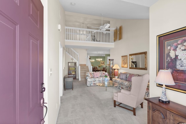 carpeted foyer with a ceiling fan, a towering ceiling, and stairway