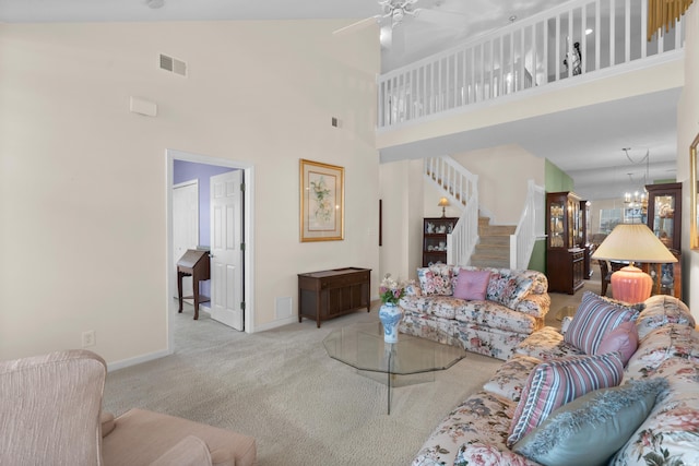 carpeted living area with ceiling fan, a towering ceiling, visible vents, stairway, and baseboards
