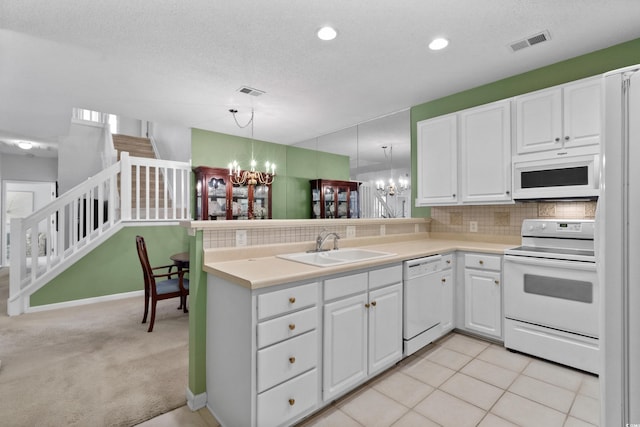 kitchen featuring a notable chandelier, white appliances, a peninsula, white cabinetry, and visible vents
