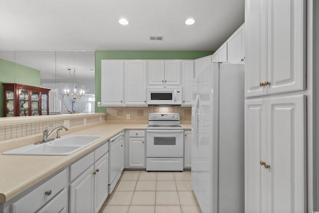 kitchen featuring an inviting chandelier, a sink, white appliances, decorative backsplash, and visible vents