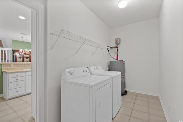 washroom featuring laundry area, washer and dryer, baseboards, water heater, and light tile patterned floors