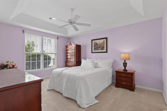 bedroom featuring light colored carpet, baseboards, visible vents, and a raised ceiling