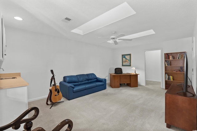 office space with ceiling fan, light colored carpet, a skylight, visible vents, and a sink