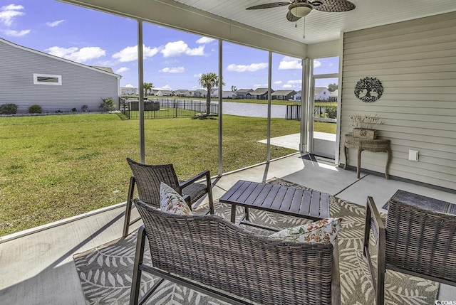 sunroom featuring a ceiling fan, a residential view, and a water view
