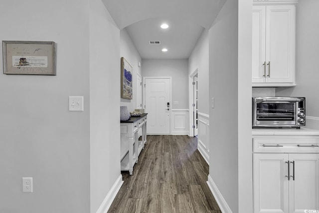 hallway with visible vents, dark wood finished floors, a toaster, baseboards, and recessed lighting