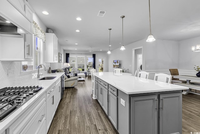 kitchen featuring a kitchen island, visible vents, stainless steel gas cooktop, a sink, and gray cabinetry