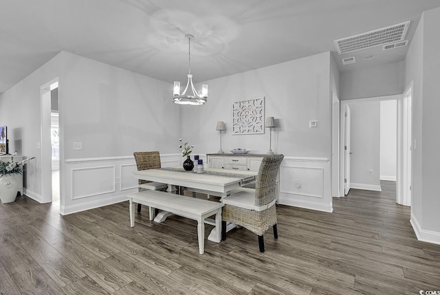 dining room featuring visible vents, wainscoting, dark wood-style floors, a chandelier, and a decorative wall