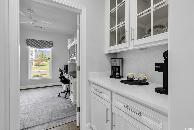 bar featuring decorative backsplash, ceiling fan, visible vents, wood finished floors, and baseboards