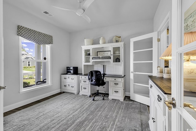 office area with a ceiling fan, visible vents, wood finished floors, built in study area, and baseboards