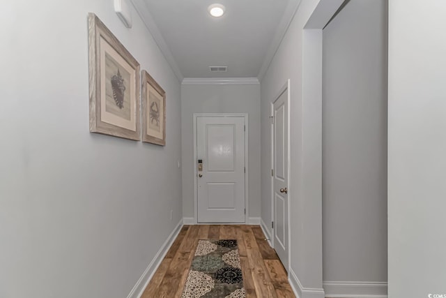 doorway featuring crown molding, baseboards, visible vents, and light wood-style flooring