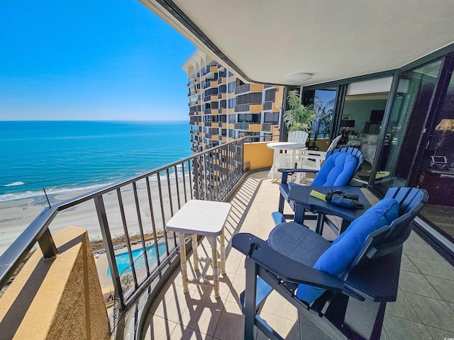 balcony with view of water and beach and view of pool