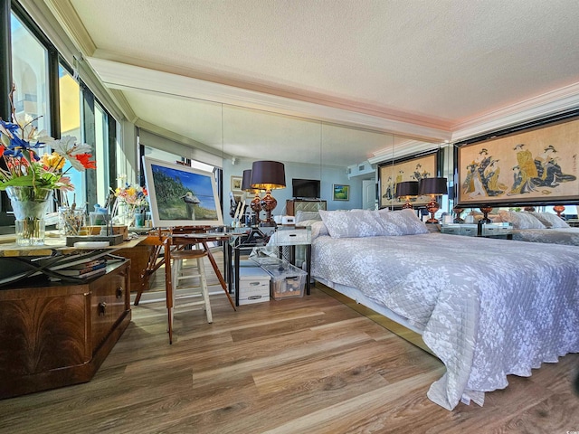 bedroom featuring crown molding, wood finished floors, and a textured ceiling