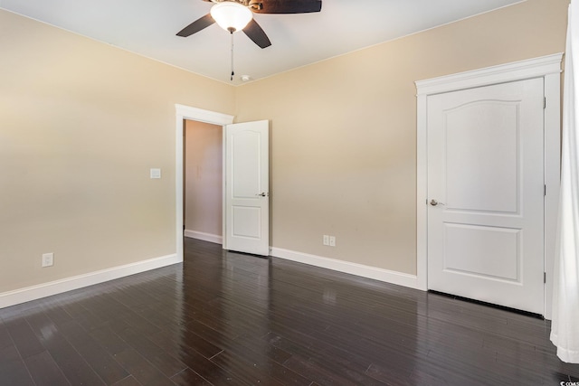 empty room featuring baseboards, a ceiling fan, and dark wood finished floors