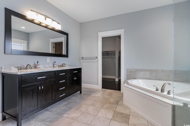 bathroom with double vanity, a bath, a sink, baseboards, and a spacious closet