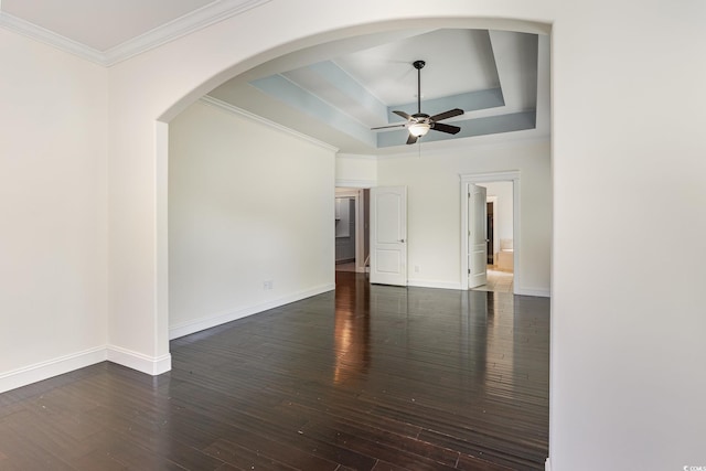 empty room with crown molding, hardwood / wood-style floors, baseboards, a raised ceiling, and a ceiling fan