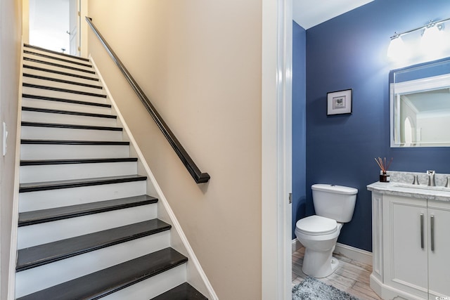 half bath featuring vanity, baseboards, toilet, and wood finished floors