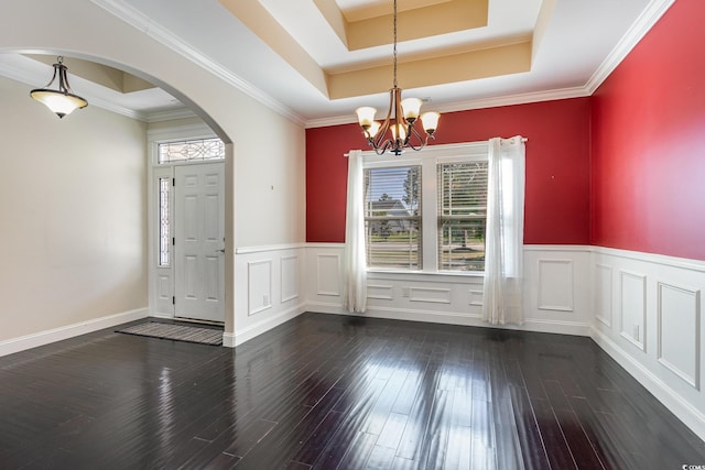 unfurnished dining area featuring an inviting chandelier, arched walkways, a wainscoted wall, and hardwood / wood-style flooring