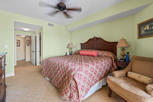bedroom featuring visible vents, baseboards, ceiling fan, and light carpet