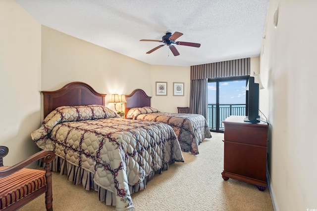 carpeted bedroom with a textured ceiling, ceiling fan, and access to exterior