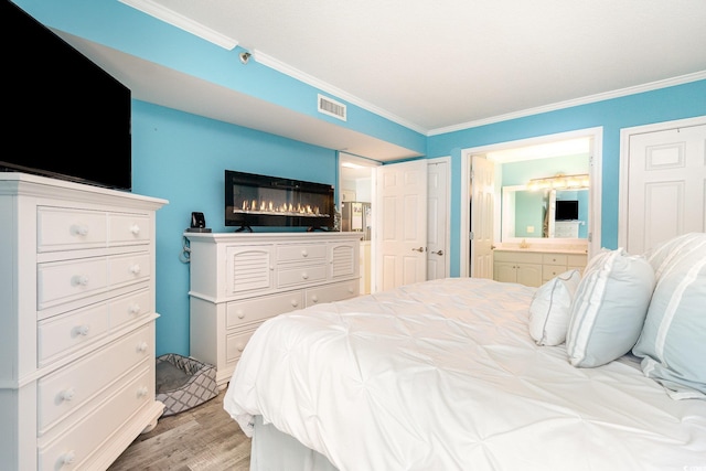 2507 S Ocean Blvd Unit 403, North Myrtle Beach, SC 29582 - bedroom featuring connected bathroom, visible vents, light wood-style flooring, and ornamental molding