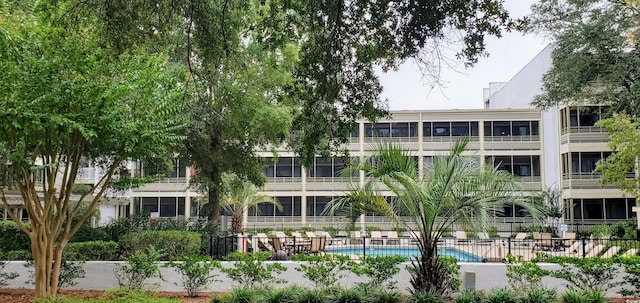view of property with a community pool and fence