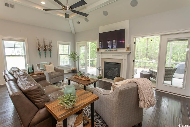 living area with a fireplace with flush hearth, lofted ceiling with beams, a ceiling fan, and visible vents