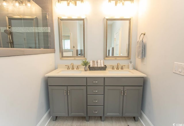 full bath featuring double vanity, baseboards, and a sink