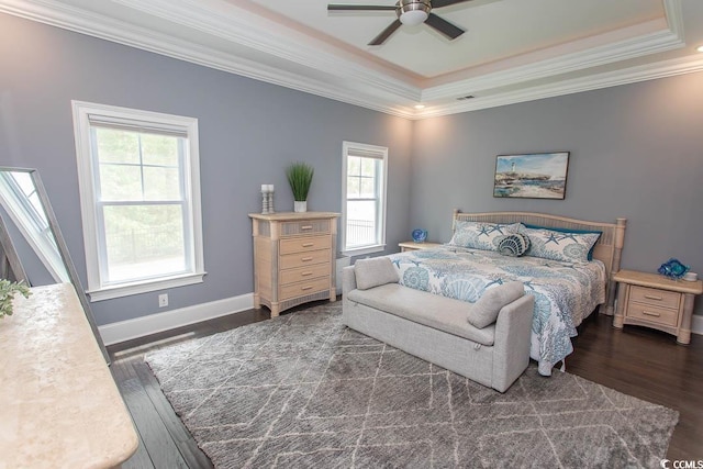 bedroom with ornamental molding, wood finished floors, baseboards, a tray ceiling, and a ceiling fan