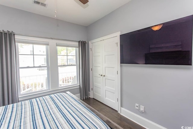 bedroom featuring ceiling fan, baseboards, visible vents, dark wood-style floors, and a closet